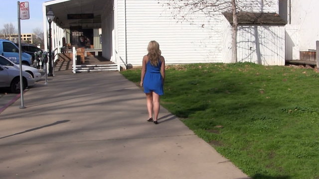 Blond Woman In Blue Dress Walking Outdoors
