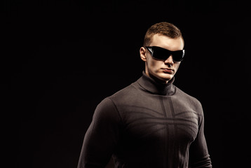 Combat muscled action hero man wearing shirt with pants and sunglasses. Studio shot. Robocop Style