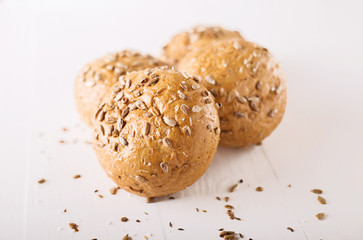 Four buns with seeds on a light wooden background, top view 