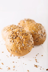 Four buns with seeds on a light wooden background, top view 