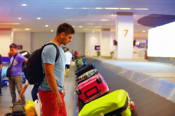 young adult man, passenger waiting for luggage in airport terminal