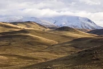 Foto op Canvas glooiende heuvels voor een wolk gedrapeerde besneeuwde butte © jimagez