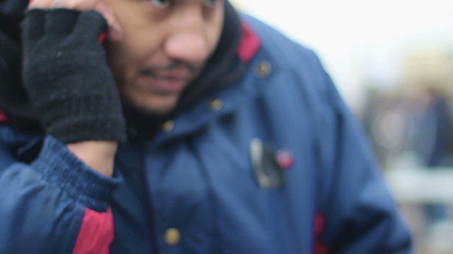 Happy manual worker talking over phone outdoors, male migrant calling home