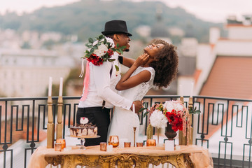 Stylish african wedding couple having fun on the balcony with luxury golden table in oriental style...