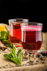 Cups of teas with cinnamon sticks and stars anise, mint leaves and sliced fruits

