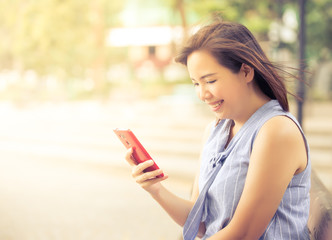 Happy women smiling in park and looking at smart phone