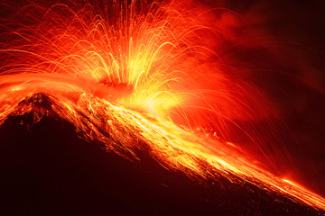 A close-up image of a volcanic eruption with red hot lava flowing down the mountain, exploding...