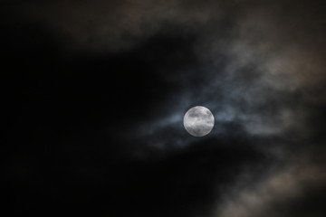Naklejka na ściany i meble Full moon with dark clouds passing by.