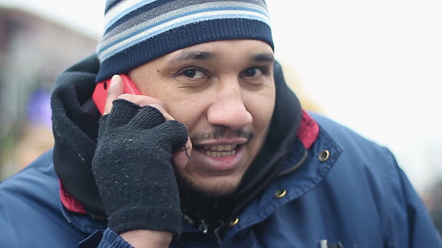 Happy male immigrant wearing shabby work clothes having phone conversation