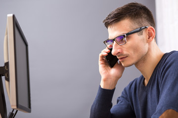 Young business man in glasses speaking on phone