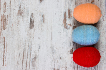 Easter eggs wrapped woolen string on wooden background, copy space for text, decoration for Easter