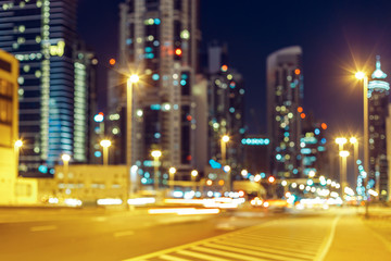 Fototapeta na wymiar Blurred nighttime cityscape with illuminated modern architecture and street lights. Downtown Dubai, UAE.