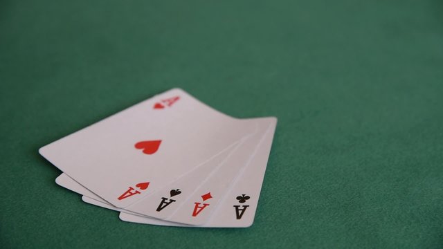 A hand of a woman showing four aces on the green cloth