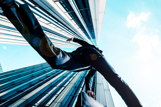 カメラの上を飛び越えるビジネスマン,ローアングル,ビルの背景