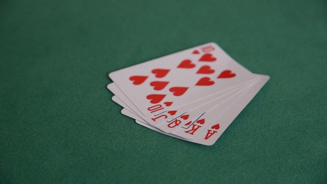 A hand of a woman showing royal flush on the green cloth