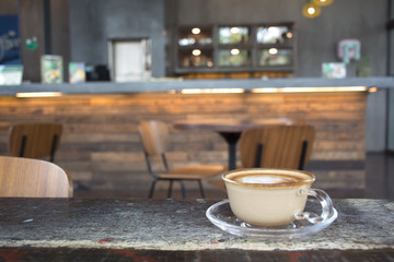 Hot Latte in a cup on wooden table in cafe  blur background
