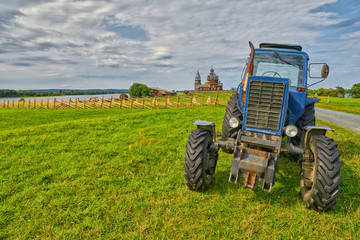Old rusty tractor on a field with monastery in background
