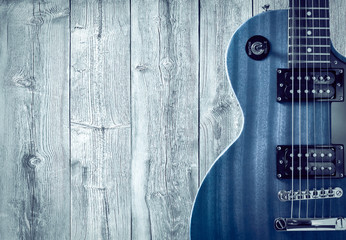 Part of the blue electric guitar on wooden background. A place for writing of the text.
