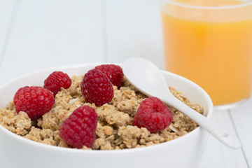 Granola in a bowl with raspberries and orange juice, muesli