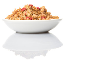 Breakfast cereal with dried raspberry fruit pieces in white bowl over white background