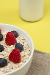 Rolled oats (oat flakes) in a bowl with raspberries, blueberries