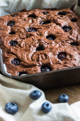 Chocolate brownie with blueberries in the baking pan on a wooden table