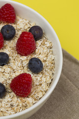 Rolled oats (oat flakes) in a bowl with raspberries, blueberries