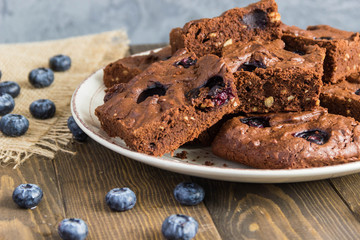 Chocolate brownie with peanuts, blueberries on a wooden 