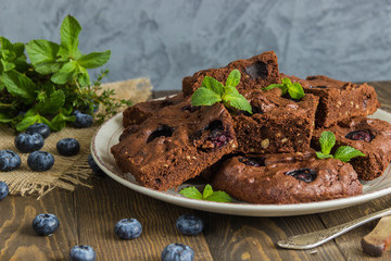 Chocolate brownie with peanuts, blueberries,mint on a wooden 
