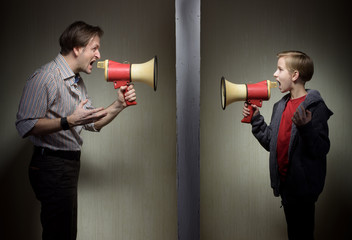 Tween son and his father yelling through the megaphones standing on either side of a wall