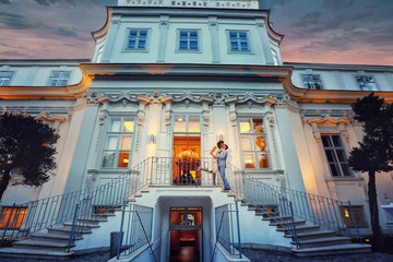 stylish groom in blue suit and bride kissing on stairs evening b