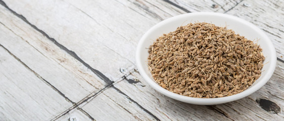 Dried aniseed in white bowl over wooden background