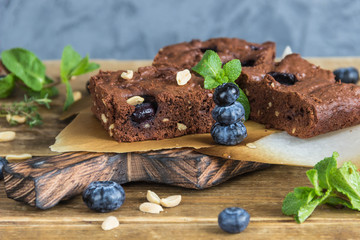 Chocolate brownie with peanuts,blueberries and mint on a wooden serving Board 