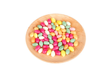 Candy eggs on wooden plate isolated on white