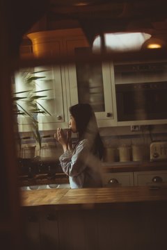 Brunette drinking coffee in front of the window