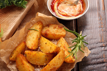 Roasted potatoes with dip and fresh salad on wooden table
