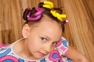 Portrait of a little girl in a dress. Curlers.
