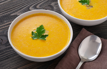 pumpkin soup with parsley leaf on dark wooden surface