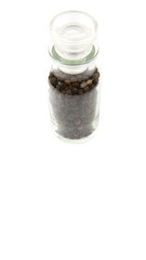 Black peppercorn in glass vial over white background