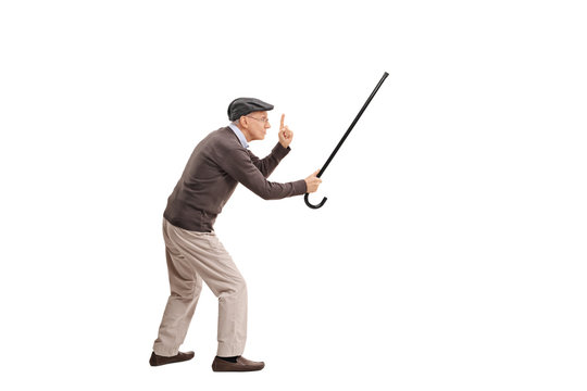 Enraged senior holding his cane as a sword