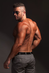 Fototapeta na wymiar shirtless muscular man in pants and sunglasses posing in studio