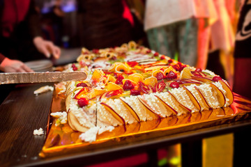 Cutting large cake with berries and fruits
