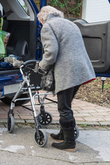 Ältere Dame mit Rollator am Auto