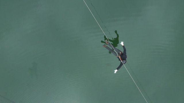 Aerial view of a person crossing a lake on the zipline