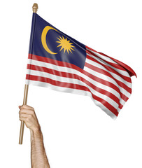 Hand proudly waving the national flag of Malaysia