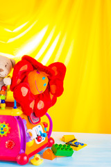 Children multicolored toys on bright yellow background