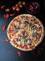 Delicious pizza with salami, tomatoes and hot peppers