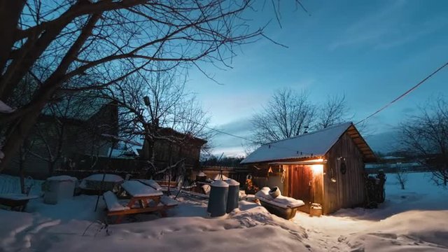 Day to night time lapse of the winter garden with wooden building illuminated by lamp