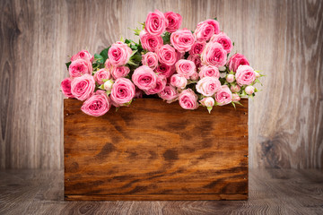 Roses in the box on wooden background

