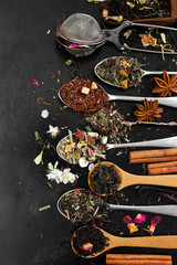 Aromatic flower tea in spoon on rustic black background.
